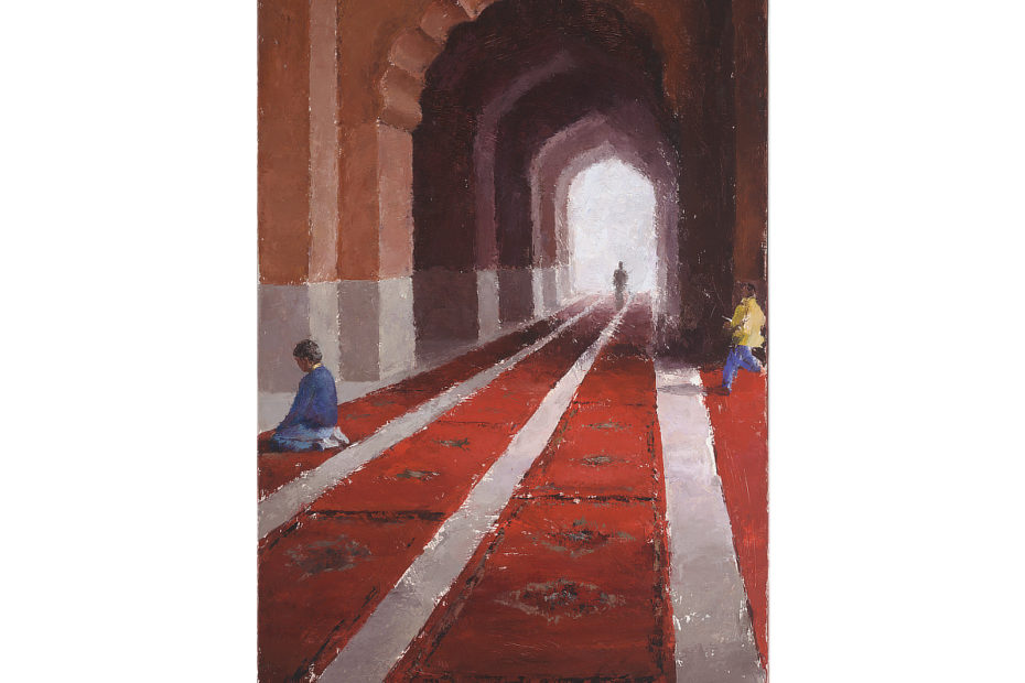 View of people inside the Jama Masjid mosque in Delhi, India, showing red carpets receding into the background underneath curved archways.