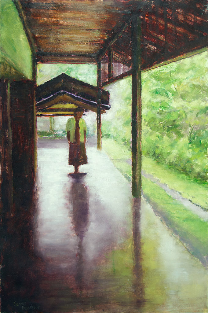Nun walking along covered deck surrounded by lush greenery at the Ryoanji Monastery in Kyoto, Japan.