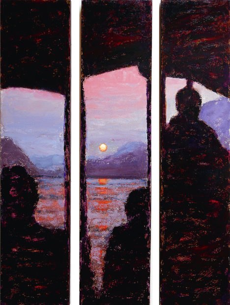 Silouettes of people on a long boat on the Mekong River, Laos, looking across the river at a sunset above distant mountains.