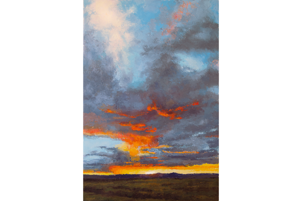 Vast open sky with bright orange, white, red and blue clouds illuminated by the sun on the horizon above the mesa in Taos, New Mexico.
